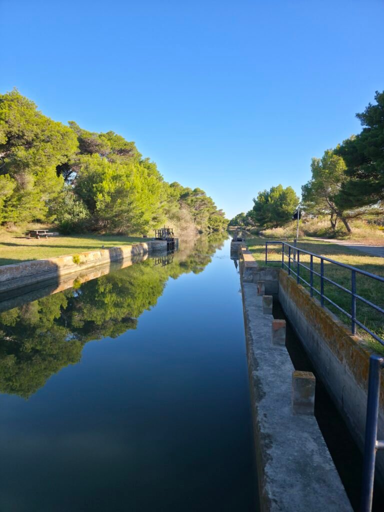 Vue paisible sur le Canal de la Robine, classé UNESCO, bordant la Réserve Sainte-Lucie, avec son chemin de halage idéal pour une randonnée à pied ou à vélo.
